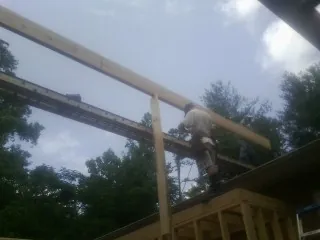 Carpenter setting a ridge beam over a new addition frame — Ice Dam Removal by Roofing Brothers in Colliers