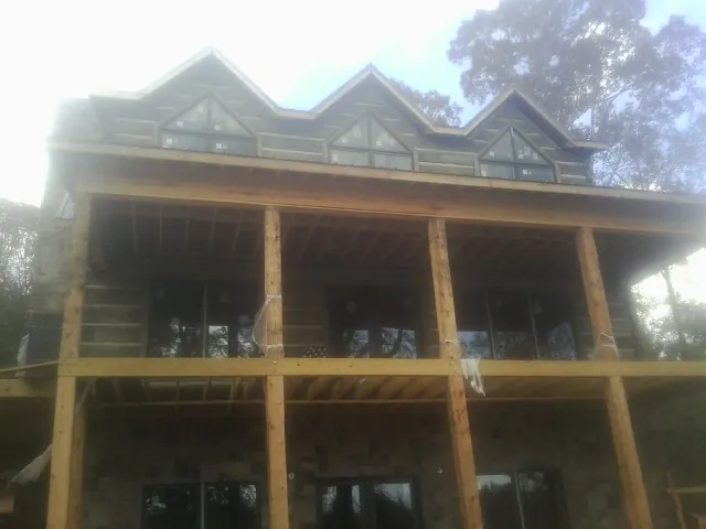 Dormers and porch framing on a large log home under construction — Roof Coating work by our crew in Colliers