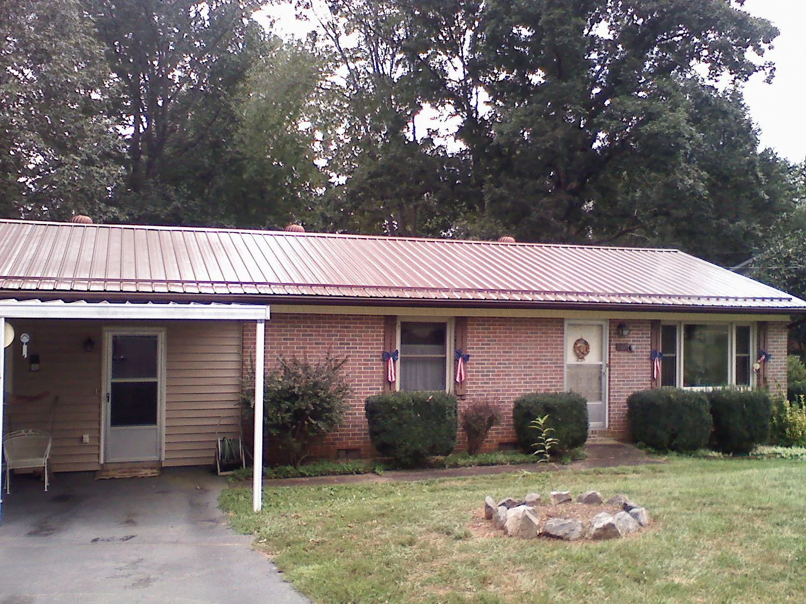 Bronze metal roof and carport on a brick ranch home — Roof Repair work by our crew in Colliers