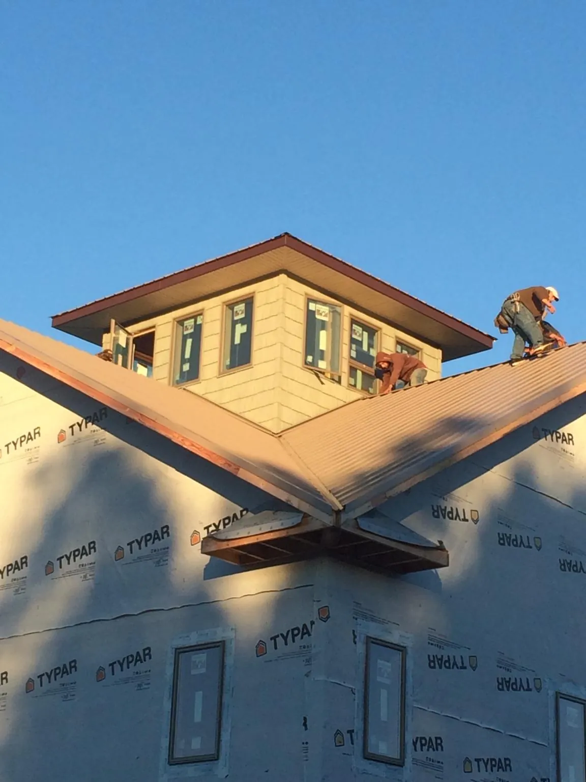 Roofers working around a rooftop cupola on a new metal roof at sunset — Roof Waterproofing in Colliers by Roofing Brothers